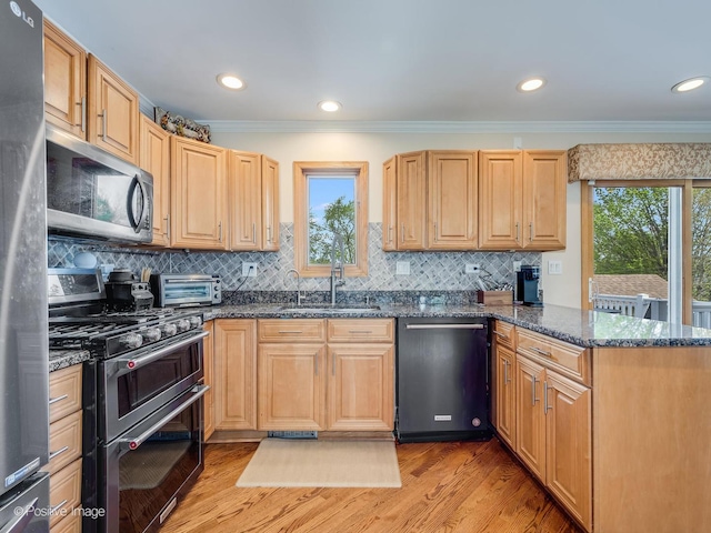 kitchen with ornamental molding, a peninsula, light wood-style floors, a sink, and appliances with stainless steel finishes