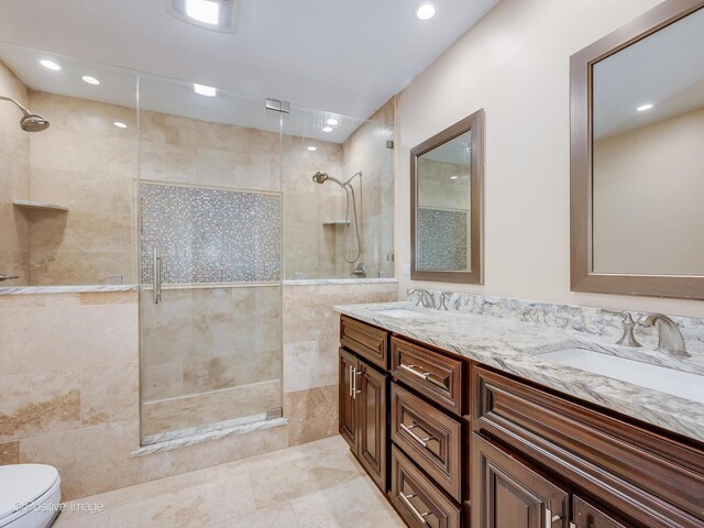 full bath featuring a sink, a shower stall, toilet, and double vanity