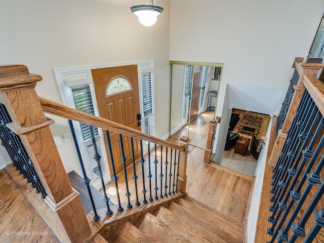 stairway with a high ceiling and wood finished floors