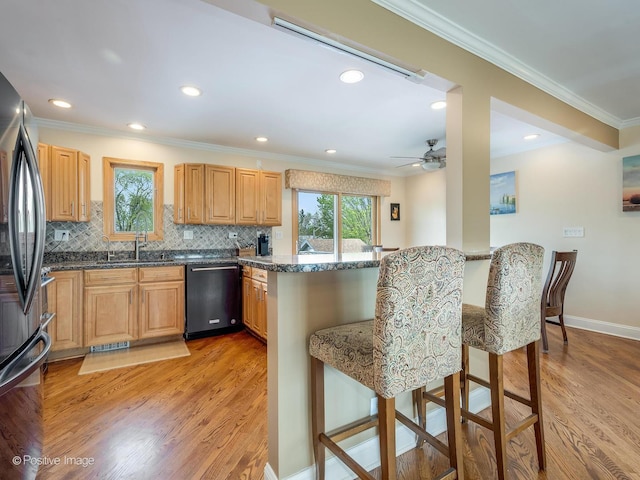 kitchen with crown molding, a breakfast bar area, a peninsula, light wood-type flooring, and dishwashing machine