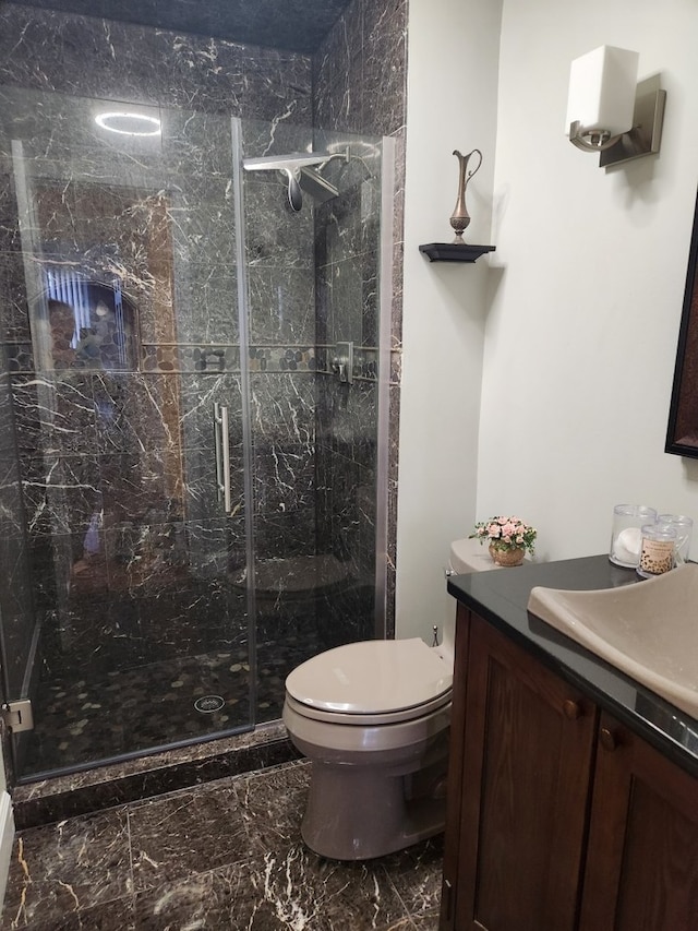 bathroom with toilet, a marble finish shower, marble finish floor, and vanity