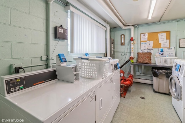 common laundry area featuring washing machine and clothes dryer, concrete block wall, and a baseboard radiator