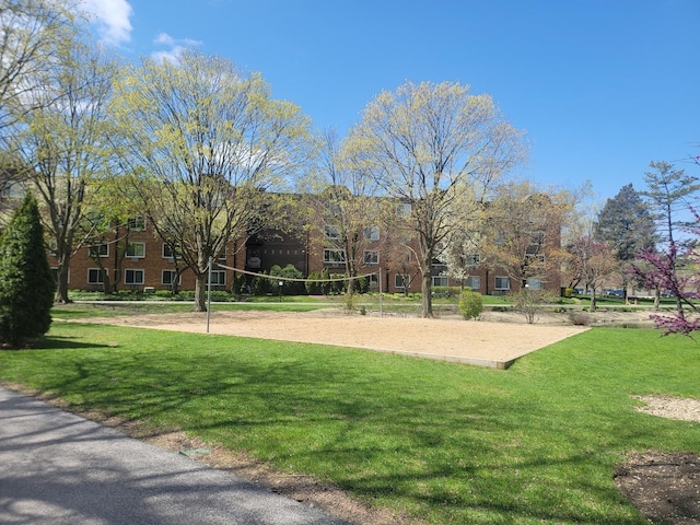 view of community with volleyball court and a lawn
