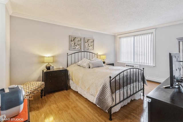 bedroom featuring crown molding, a baseboard heating unit, and wood finished floors