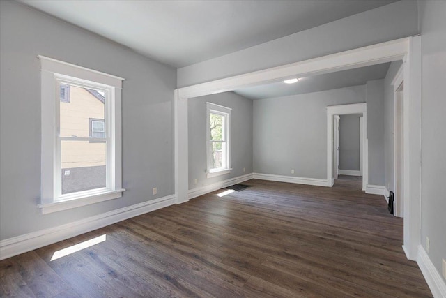 unfurnished room featuring baseboards and dark wood-style floors
