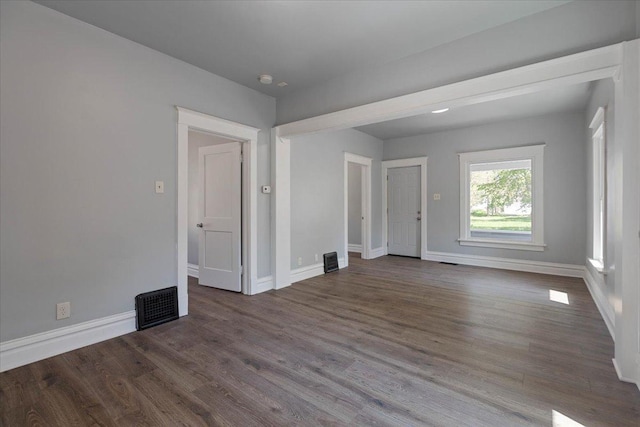 empty room featuring baseboards and dark wood-type flooring