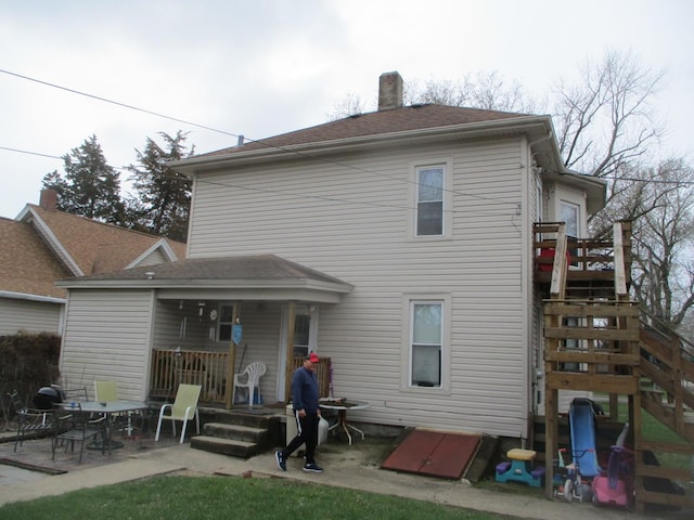 rear view of house featuring a patio area, a wooden deck, and a chimney