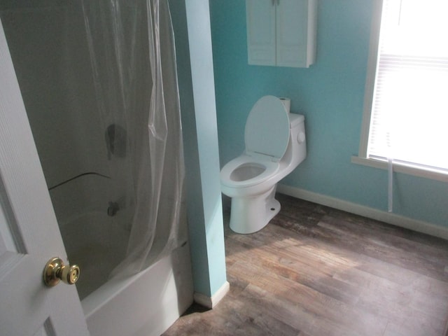 bathroom with toilet, baseboards, shower / bath combination with curtain, and wood finished floors