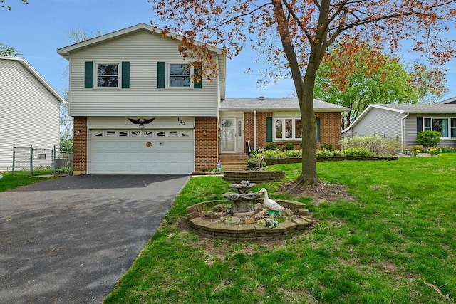 tri-level home featuring a garage, a front lawn, fence, brick siding, and driveway