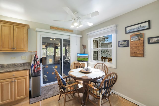 dining area featuring a ceiling fan, baseboards, and light wood-type flooring