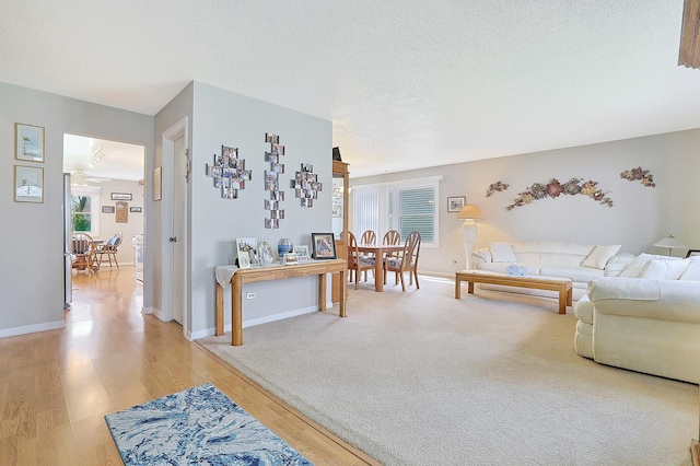 living room featuring a textured ceiling, baseboards, and light wood-style floors