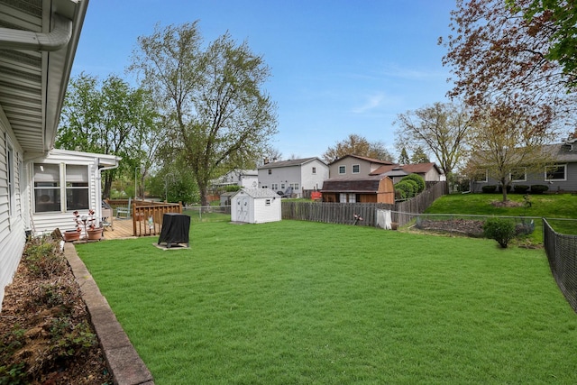 view of yard featuring a fenced backyard, a wooden deck, an outbuilding, and a shed