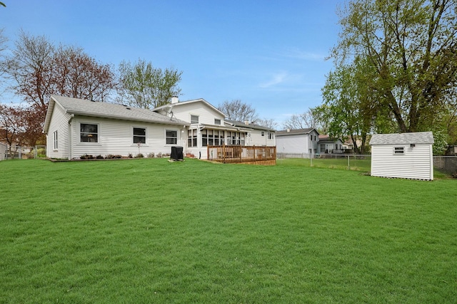 rear view of property featuring a yard, an outbuilding, a shed, and a fenced backyard