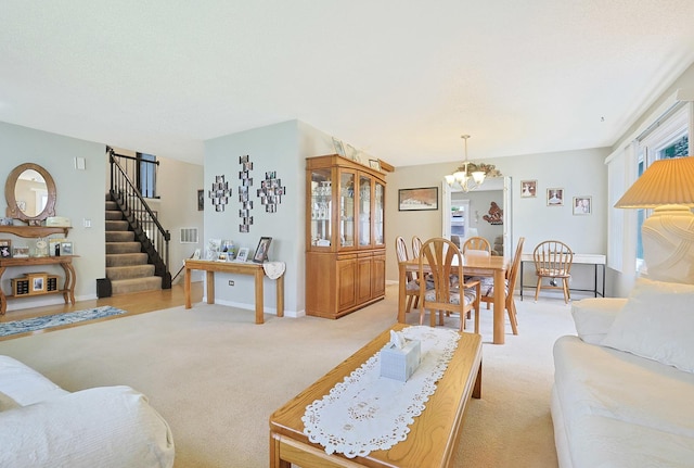 living area with light colored carpet, baseboards, a chandelier, and stairway