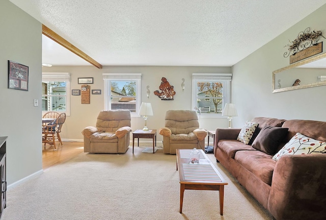 carpeted living area featuring baseboards, beamed ceiling, and a textured ceiling