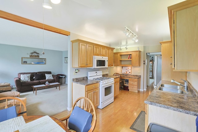 kitchen featuring light brown cabinetry, white appliances, open floor plan, a sink, and light wood-style flooring