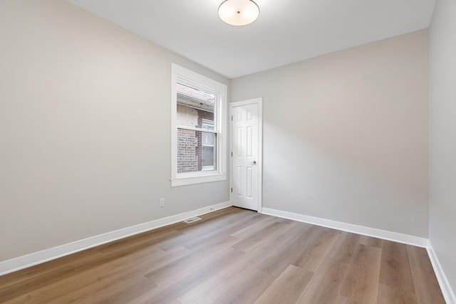 unfurnished room featuring baseboards, wood finished floors, and visible vents