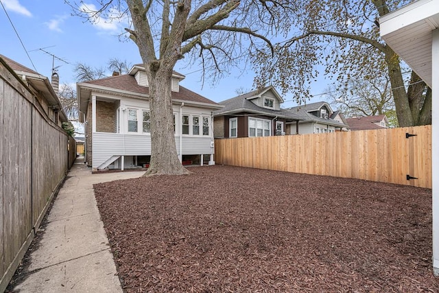 rear view of property featuring a fenced backyard and roof with shingles