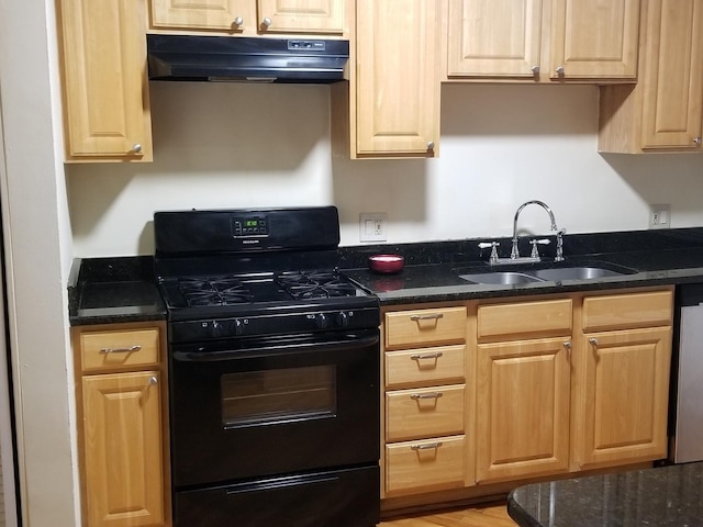 kitchen featuring a sink, black range with gas cooktop, under cabinet range hood, and dark stone countertops