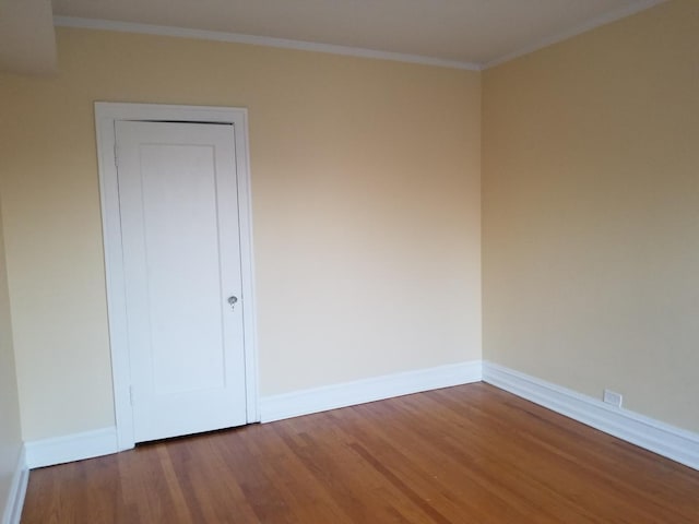 spare room featuring baseboards, ornamental molding, and wood finished floors