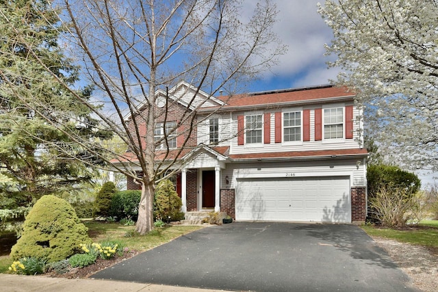 traditional home with a garage, driveway, and brick siding