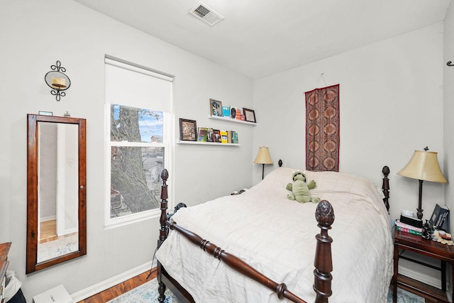 bedroom featuring wood finished floors, visible vents, and baseboards
