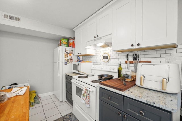 kitchen featuring white appliances, light tile patterned floors, under cabinet range hood, white cabinetry, and visible vents