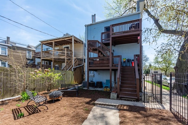 rear view of house featuring central air condition unit, stairway, a fire pit, and fence
