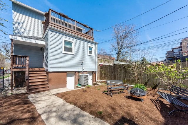 rear view of house featuring fence, stairway, and an outdoor fire pit