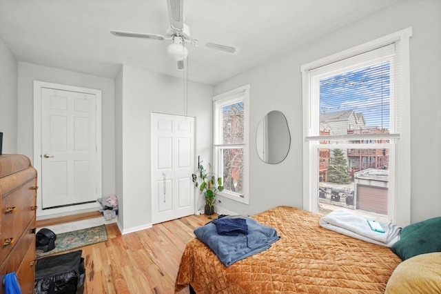 bedroom featuring a closet, light wood finished floors, a ceiling fan, and baseboards