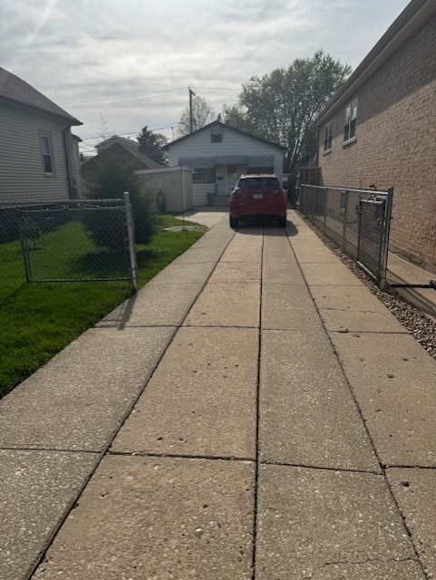 view of side of home with a yard, fence, and concrete driveway