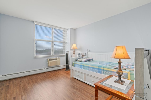 bedroom featuring a wall mounted air conditioner, baseboard heating, and wood finished floors
