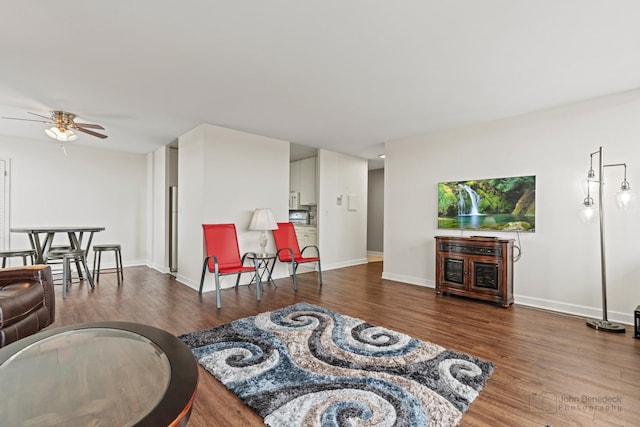 living room with baseboards, a ceiling fan, and wood finished floors