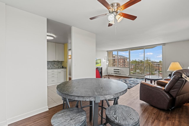 living room featuring baseboards, a wall mounted air conditioner, ceiling fan, and wood finished floors