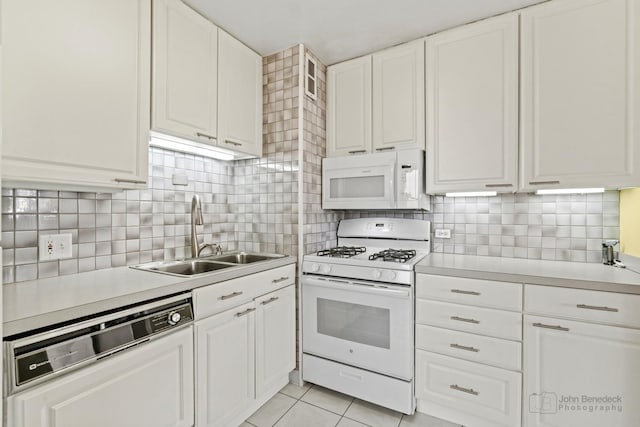 kitchen featuring a sink, white appliances, light countertops, white cabinetry, and light tile patterned floors