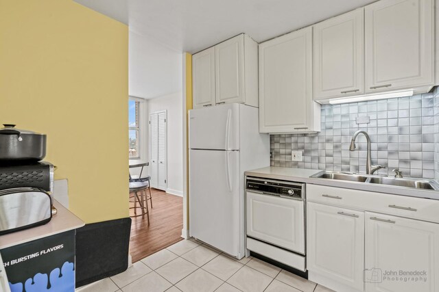kitchen with a sink, white cabinets, white appliances, and tasteful backsplash