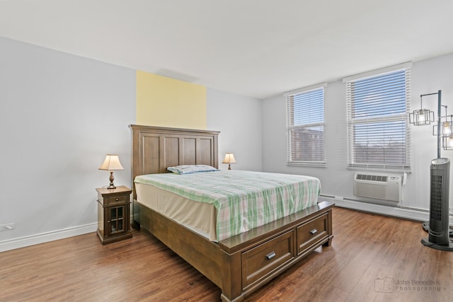 bedroom featuring baseboard heating, baseboards, a wall unit AC, and wood finished floors