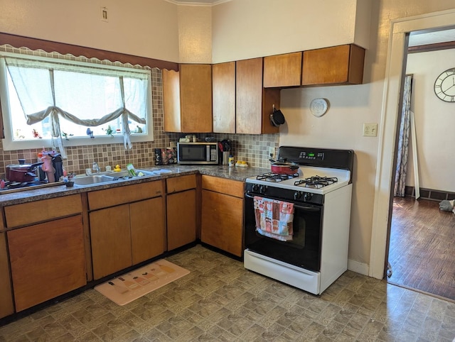 kitchen with stainless steel microwave, dark countertops, gas range, and decorative backsplash