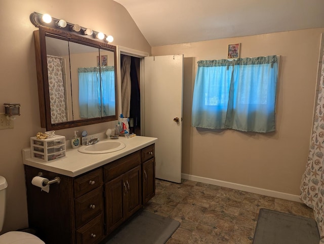bathroom featuring baseboards, vaulted ceiling, toilet, and vanity