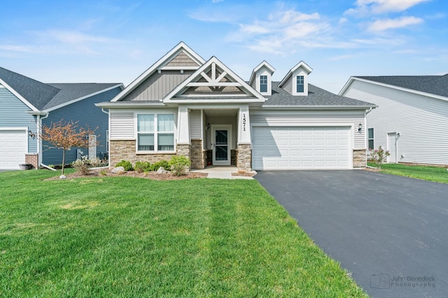 craftsman-style house featuring a garage, driveway, a front lawn, and stone siding
