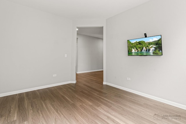 spare room with baseboards and wood finished floors