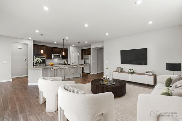 living room featuring recessed lighting, baseboards, and wood finished floors