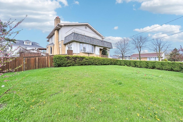 exterior space with fence, a yard, and a chimney