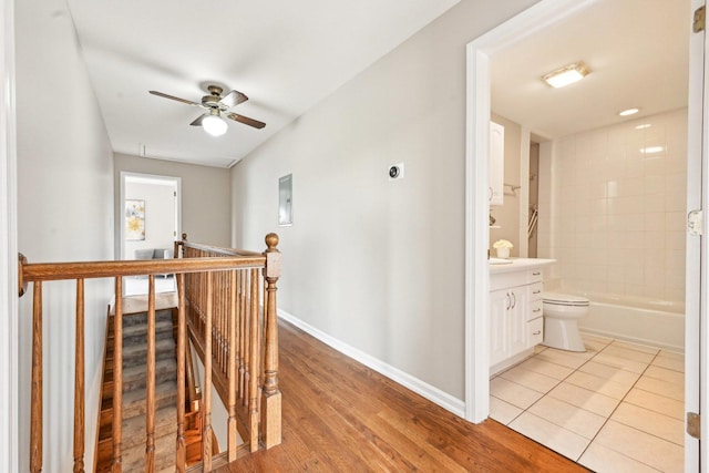 corridor featuring an upstairs landing, light wood-style flooring, and baseboards