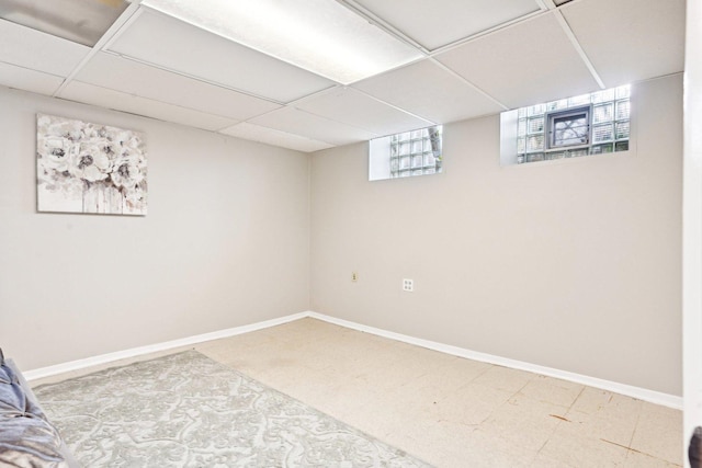 basement with a paneled ceiling, carpet flooring, and baseboards
