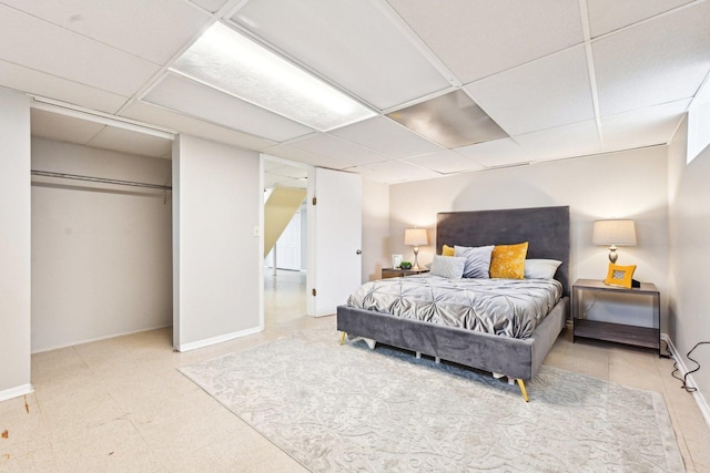 bedroom featuring a closet, a drop ceiling, and baseboards