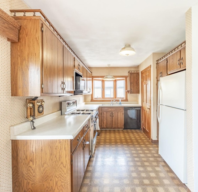 kitchen with light floors, light countertops, brown cabinets, a sink, and stainless steel appliances