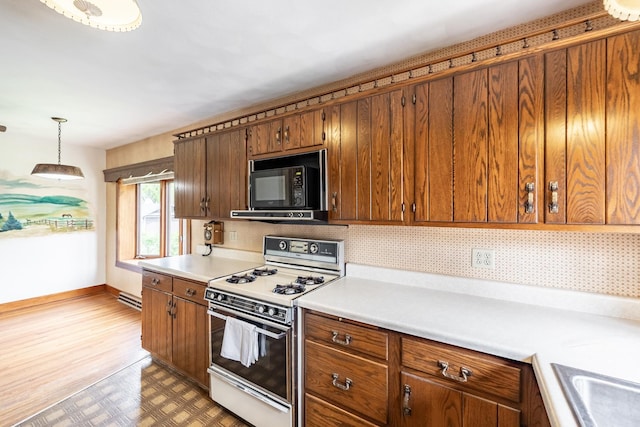 kitchen featuring brown cabinetry, black microwave, baseboards, white range with gas stovetop, and light countertops