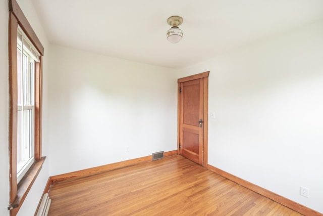 spare room with baseboards, plenty of natural light, light wood-style flooring, and visible vents