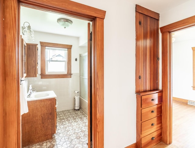 bathroom featuring vanity, visible vents, shower / bath combination with glass door, and tile walls